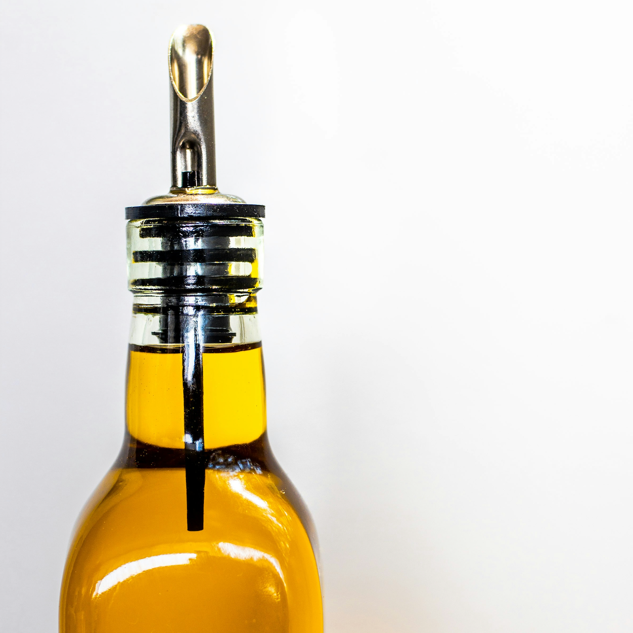 Glass bottle with a metal cap filled with olive oil on a white background