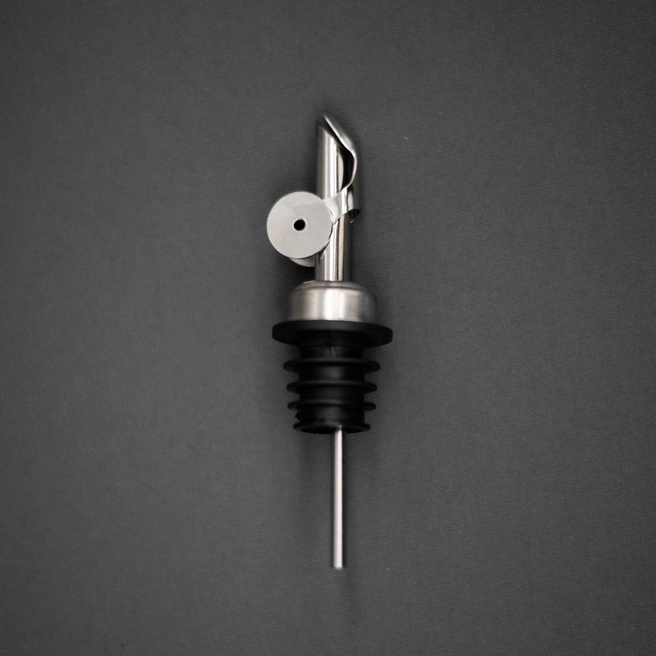 Metallic olive oil bottle pourer on a dark gray background