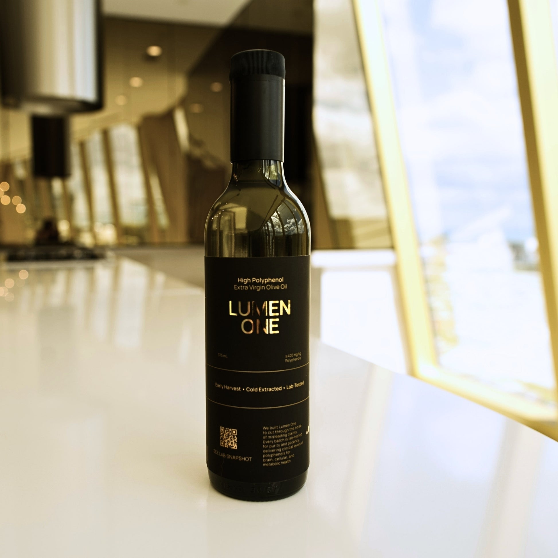 Bottle of Lumen One high polyphenol olive oil on a surface with an indoor background